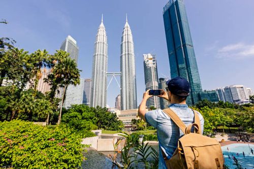 rear-view-of-a-tourist-taking-pictures-of-kuala-lumpur-skyline-with-smartphone-kuala-lumpur